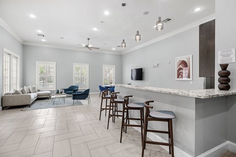 a lobby with a bar and a living room with a couch and chairs